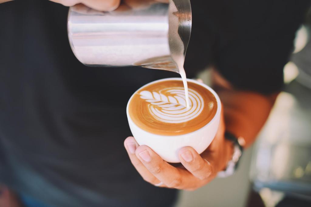 a person is pouring milk into a cup of coffee at Generator Stockholm in Stockholm