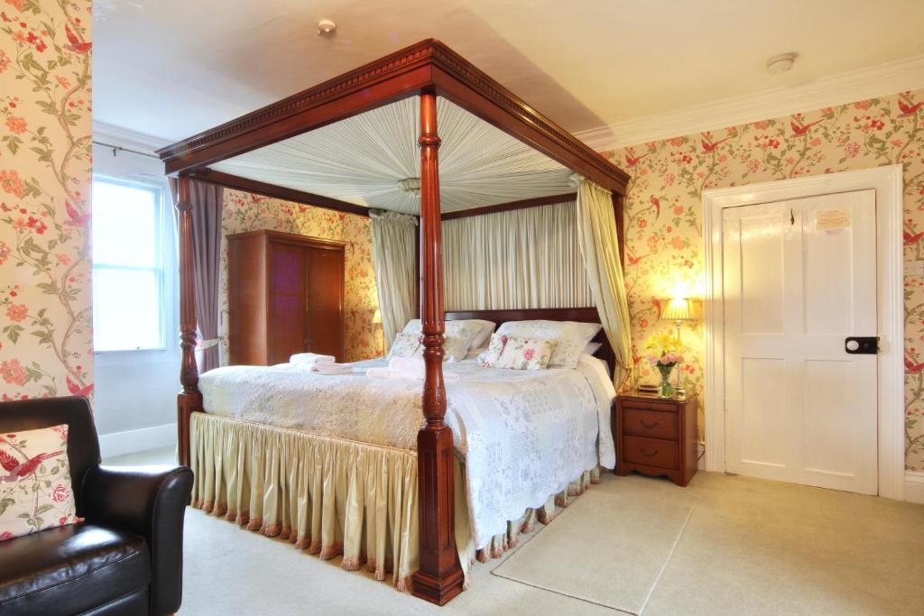 a bedroom with a canopy bed and a chair at The Old Vicarage in Leyburn