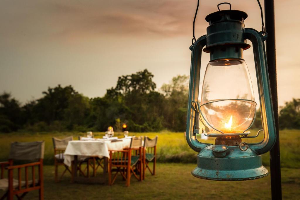 a lantern hanging on a pole with a table with chairs at Mahoora Wilpattu - by Eco Team in Wilpattu