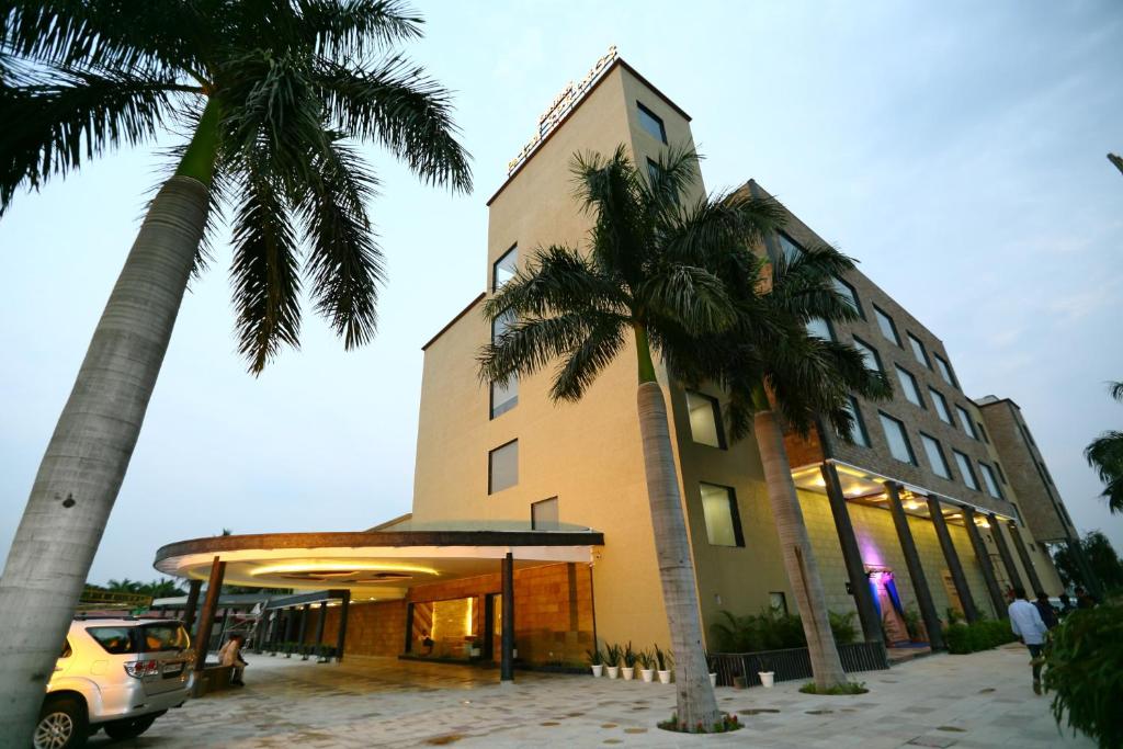 a building with palm trees in front of it at Hotel Kanha’s Palm Springs in Bhopal