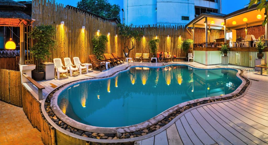 a swimming pool in a backyard with a wooden fence at Wild Orchid Villa in Bangkok