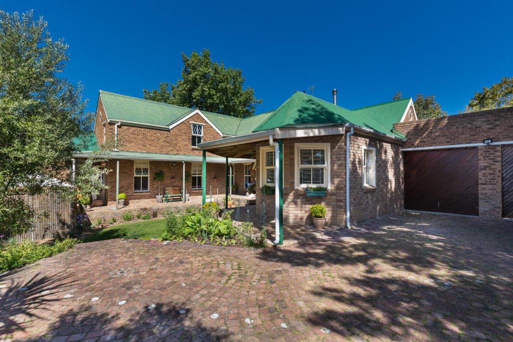 ein Backsteinhaus mit einem grünen Dach und einer Garage in der Unterkunft Rustic Manor Guest House in Tokai