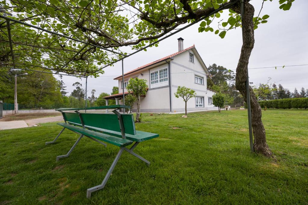 a green bench sitting in the grass in front of a house at A Chousa in Arzúa