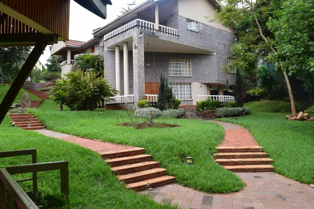 a house with a walkway in front of a yard at Adies Garden Suites in Nairobi