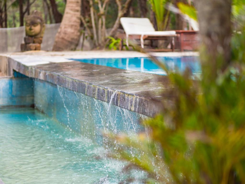 ein Schwimmbad mit einem Wasserfall in der Mitte in der Unterkunft Le Domaine De Tam Hai Resort in An Hòa