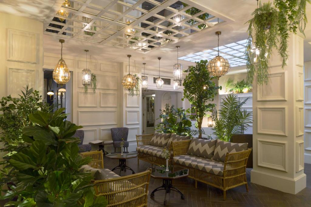 una hall con divano, piante e lampadari a braccio di ICON Wipton a Madrid
