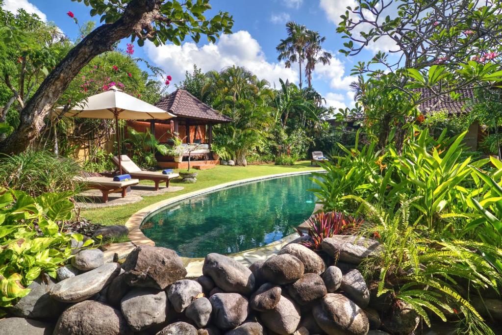a swimming pool in a garden with a rock wall at Villa Plawa Asri in Seminyak