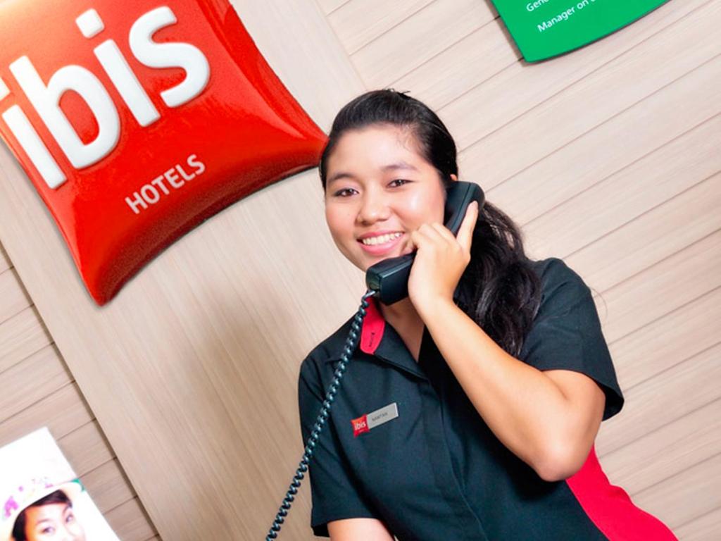 a woman talking on a cell phone in front of a store at Ibis Phuket Kata in Kata Beach