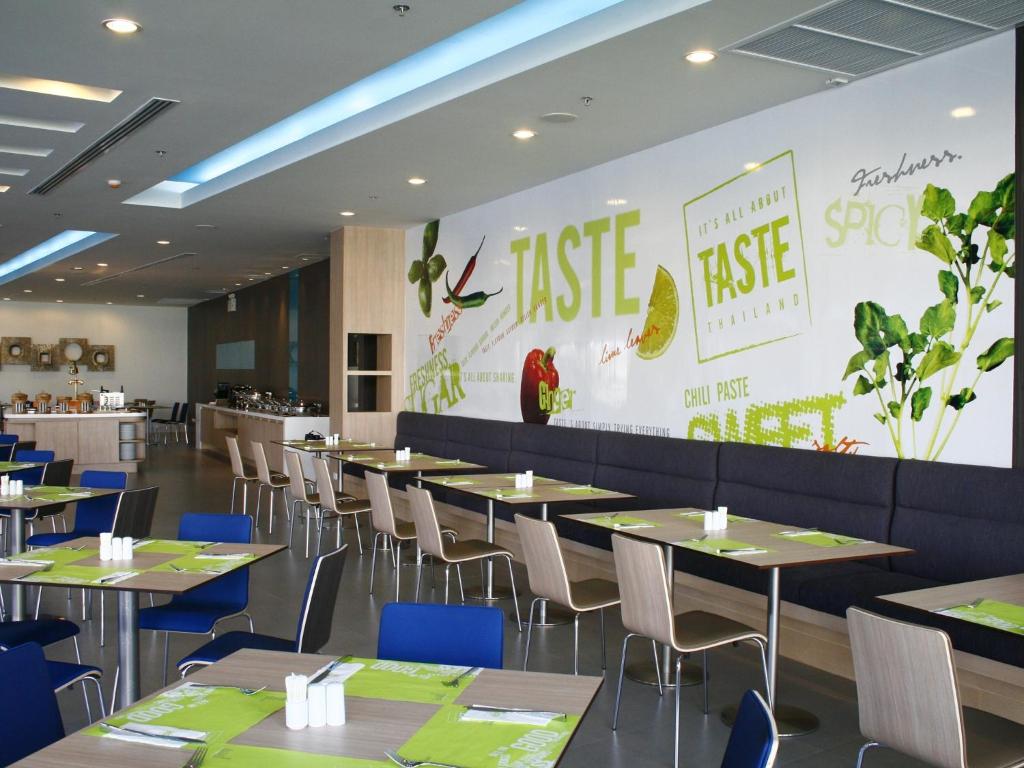 a dining room with tables and chairs and a large wall at Ibis Phuket Kata in Kata Beach