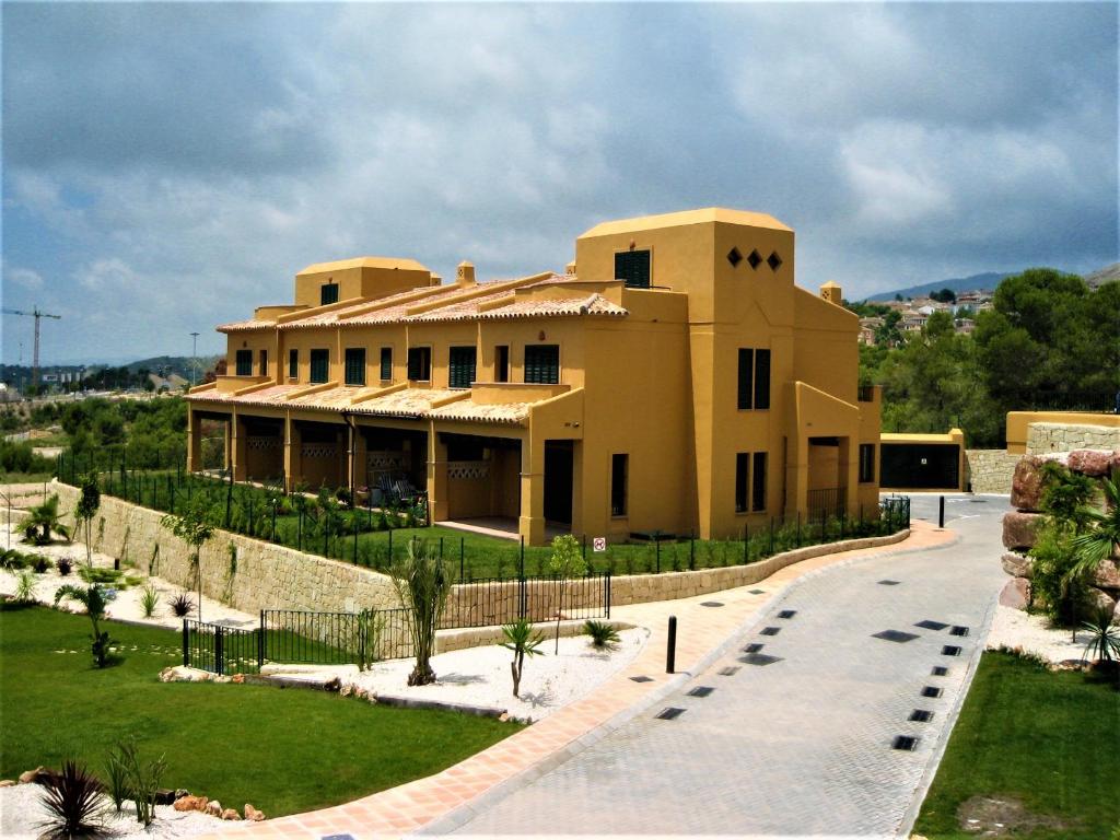 une grande maison jaune avec une allée. dans l'établissement Sierra Cortina jardín, sol y playa, à Finestrat