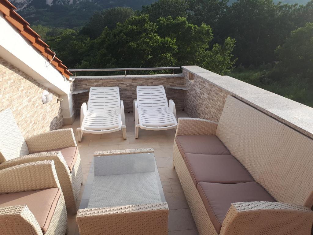 a balcony with chairs and couches on a roof at Ruzmarinka 4* in Baška