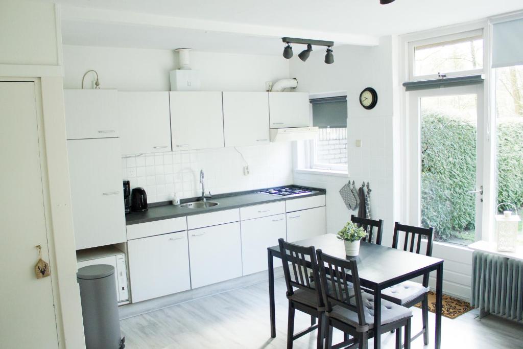 a kitchen with white cabinets and a table and chairs at Knusse Natuur Bungalow Hartje Veluwe in Otterlo