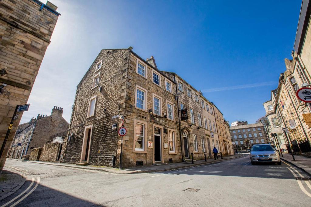 un antiguo edificio de piedra al lado de una calle en The Sun Hotel & Bar, en Lancaster