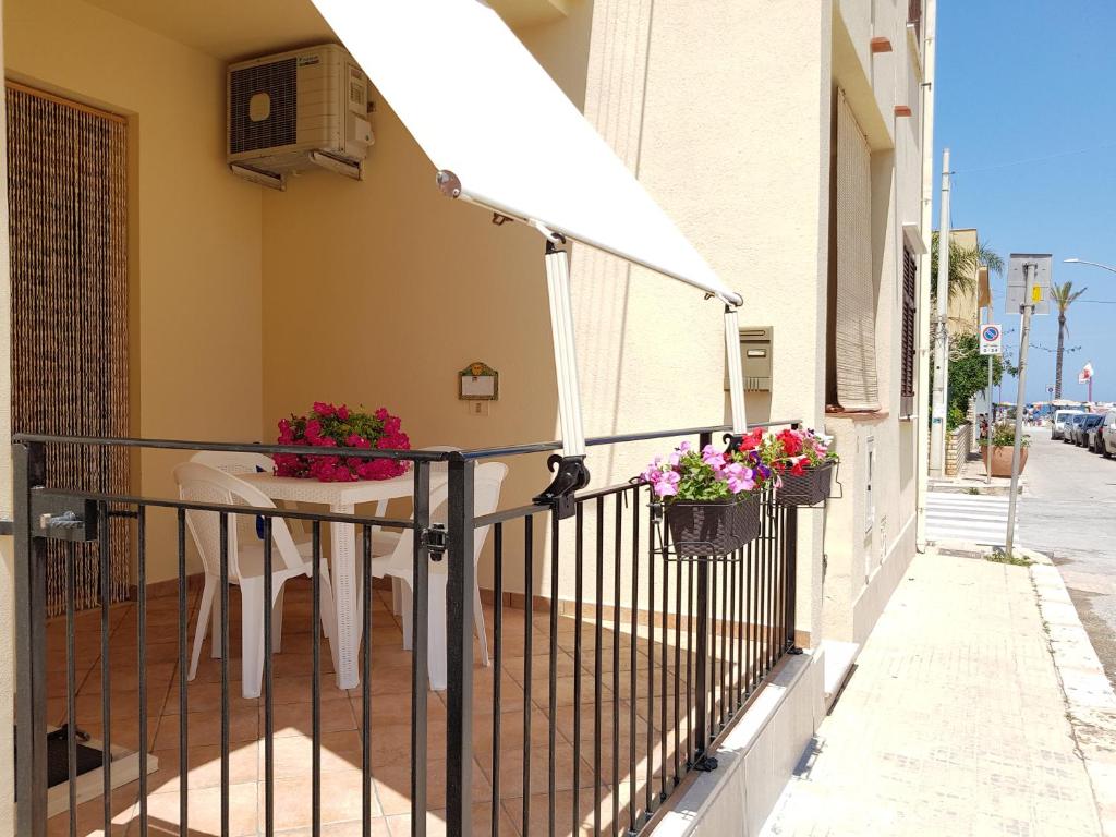 a balcony with a table and flowers on a building at Appartamento Mazzini 8 in San Vito lo Capo