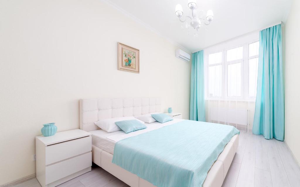 オデッサにあるFamily Apartments Aquamarine of Arcadiaの白いベッドルーム(ベッド1台、青いカーテン付)