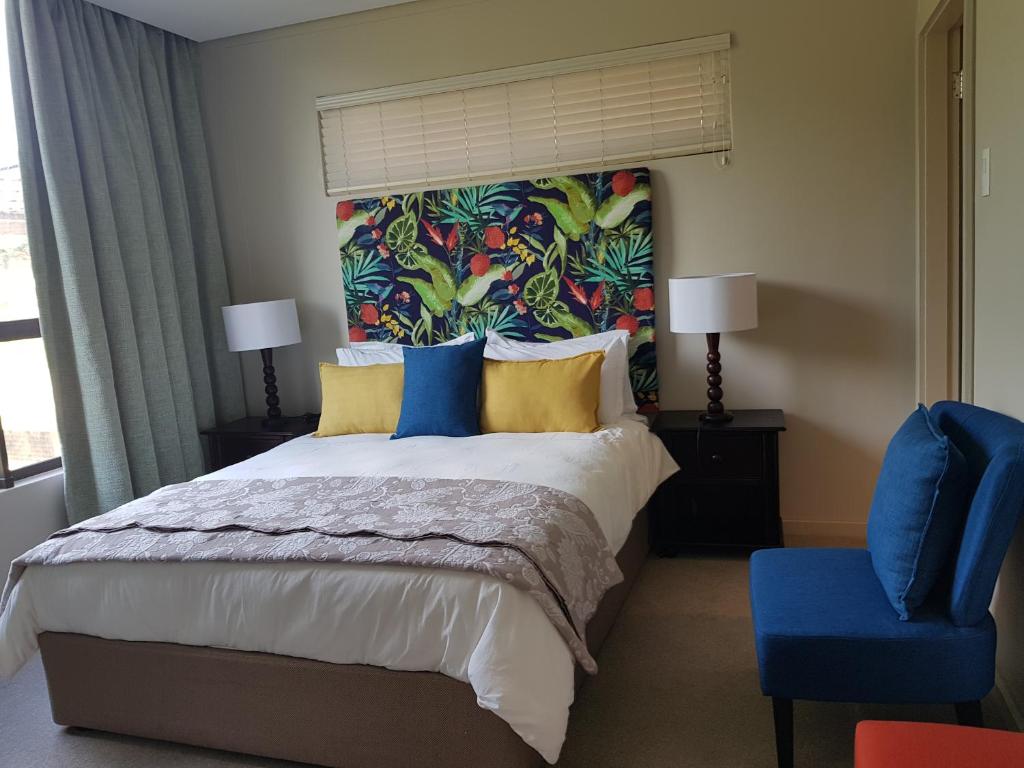 a bedroom with a large bed and a blue chair at Zimbali Suite 524 in Ballito