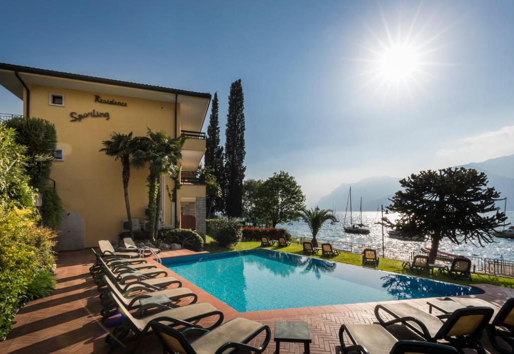a pool with chaise lounge chairs next to a building at Residence Sporting in Malcesine