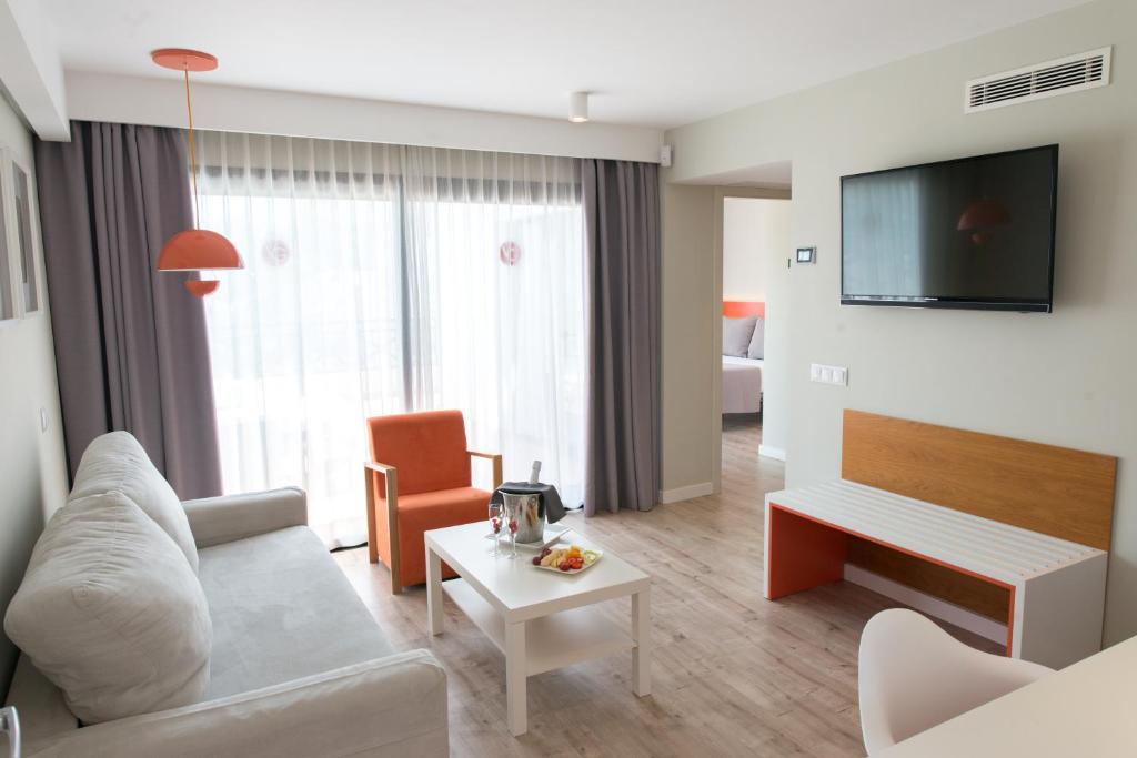 a living room with a couch and a tv at Vanilla Garden Boutique Hotel - Adults Only in Playa de las Americas