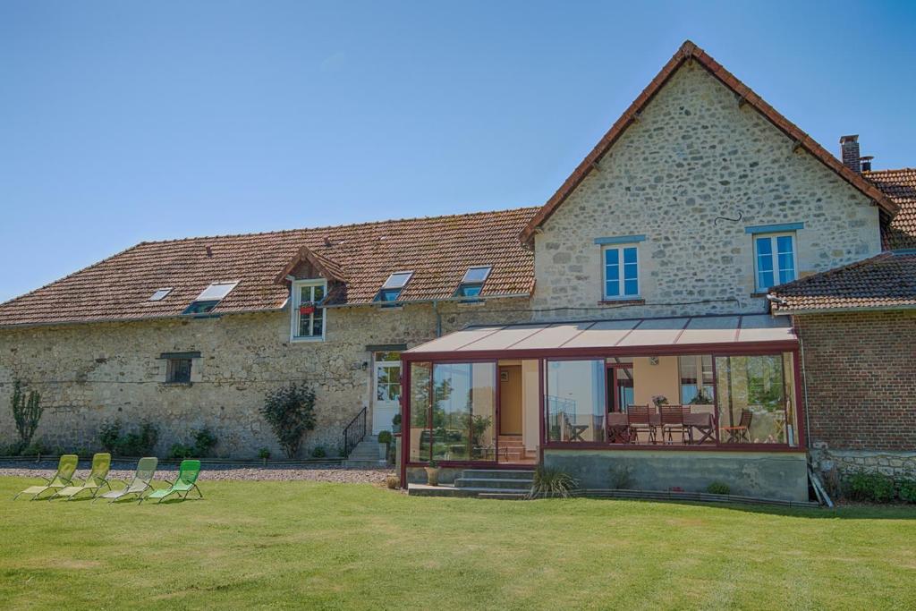 a house with chairs and a conservatory in the yard at Au Jardin Fleuri in Vauxaillon