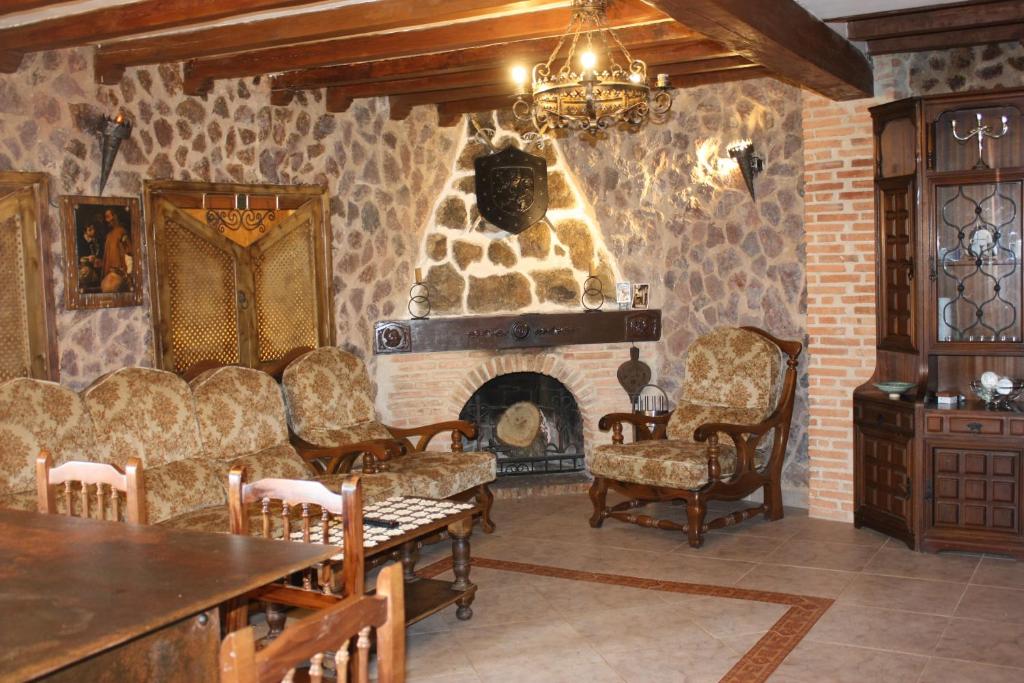 ミランダ・デル・カスタニャルにあるCasa Rural El Palatinoの石造りの暖炉と椅子付きのリビングルーム