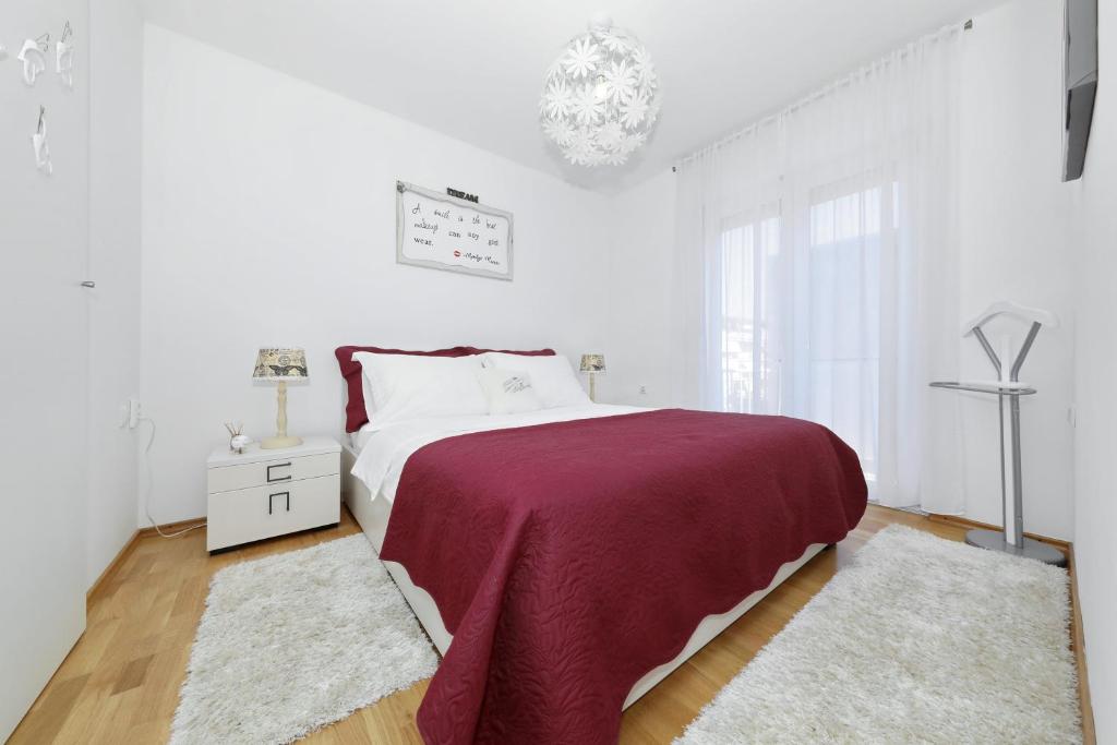 Habitación blanca con cama grande y lámpara de araña. en Luxury Apartman Rita, Center en Zadar