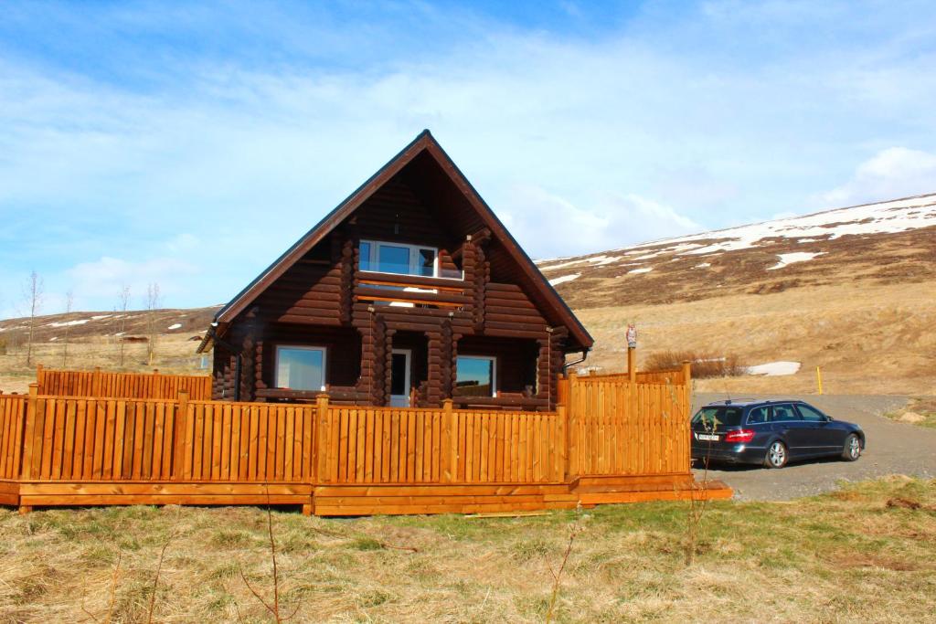 eine kleine Holzhütte mit einem Auto, das vorne geparkt ist in der Unterkunft Akureyri Log Cottage in Akureyri