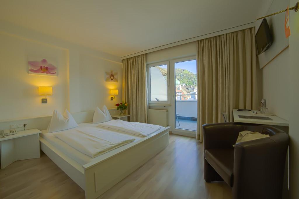 ein Hotelzimmer mit einem Bett und einem Stuhl in der Unterkunft Hotel Central in Bregenz