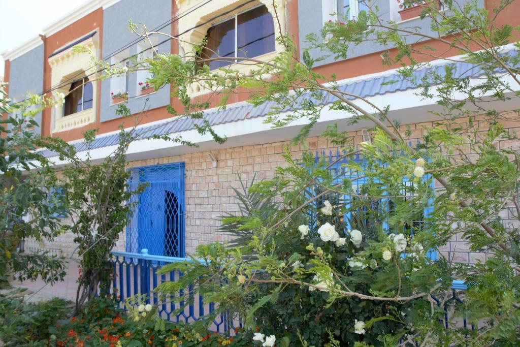 un edificio con una puerta azul y algunos árboles en L'Hirondelle de Kelibia : Chez Amou en Kelibia