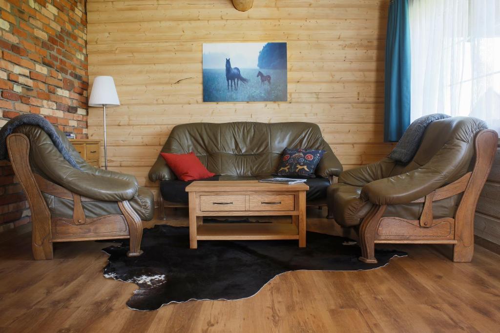 a living room with two chairs and a leather couch at Kalniaus-Sodyba in Barkellai