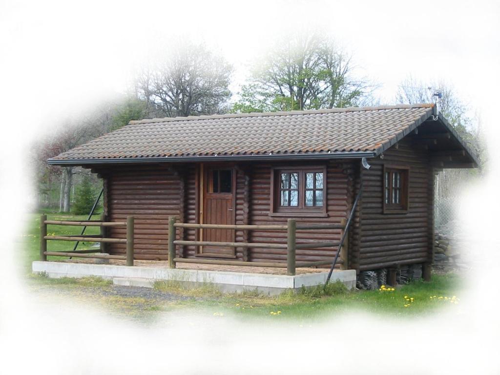 a small log cabin with a wooden porch at Camping du Meygal in Saint-Julien-Chapteuil