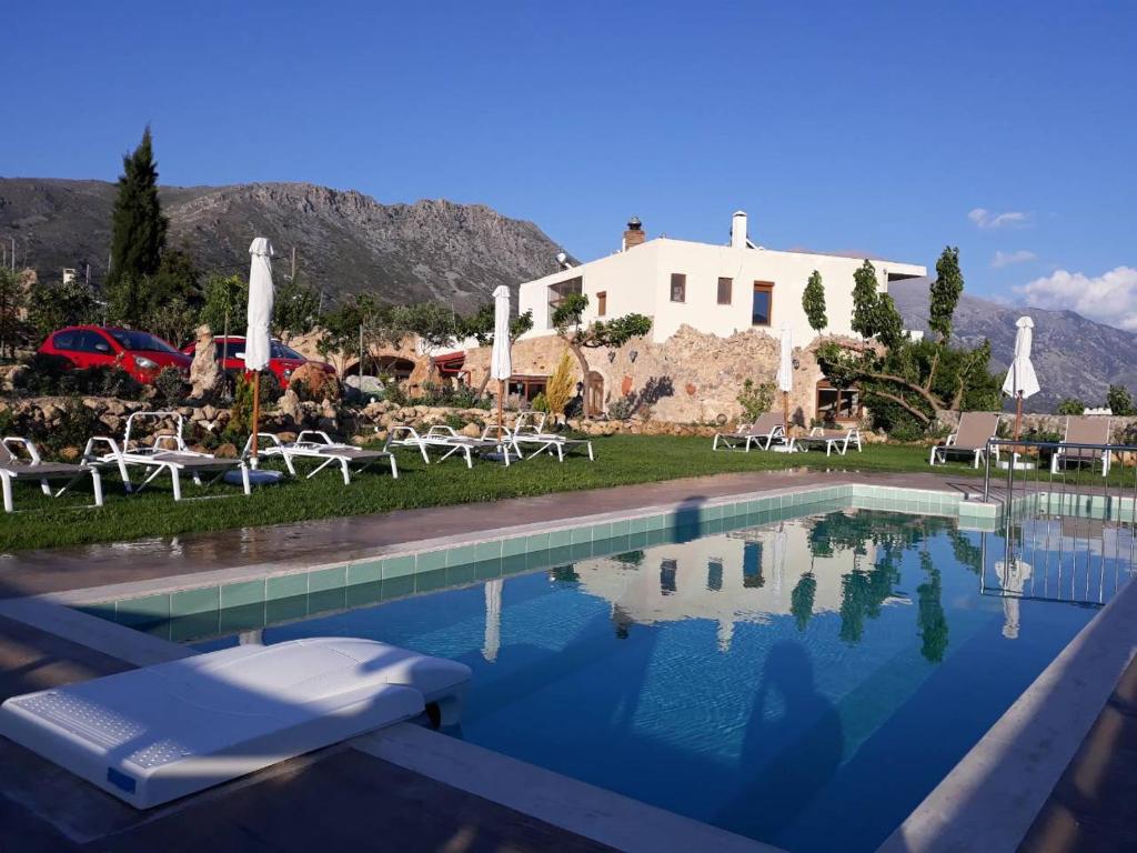 a pool with chairs and a house in the background at Aravanes in Thrónos