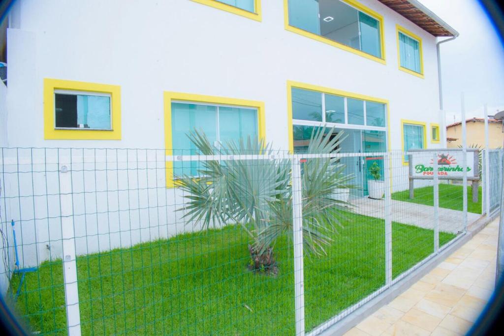 a fence in front of a house with a palm tree at Pousada Barreirinhas in Barreirinhas