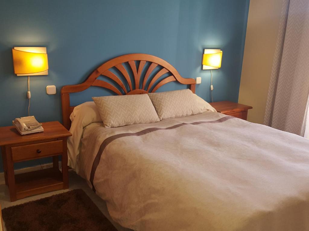a bedroom with a large bed with two night stands and two lamps at Hotel Laberinto in Sigüenza