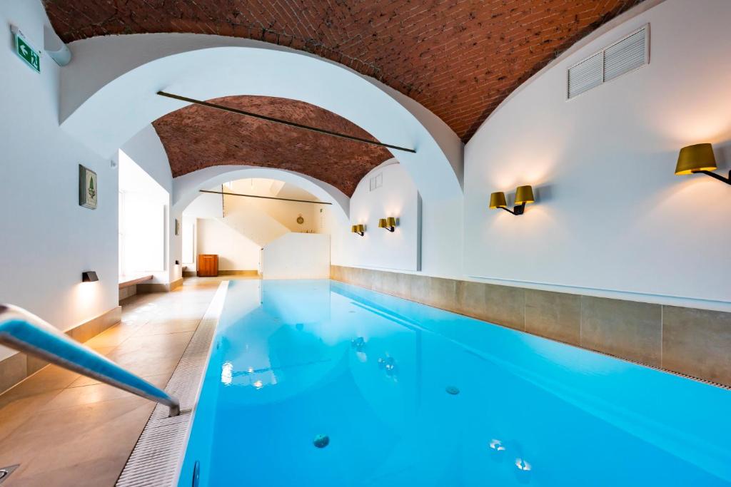 an indoor swimming pool with blue water in a building at Parkhotel Graz - Traditional Luxury in Graz