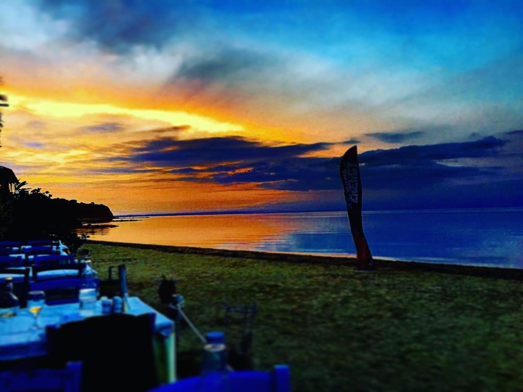 a sunset on a beach with a sign in the foreground at Halkidiki Rooms in Nea Fokea