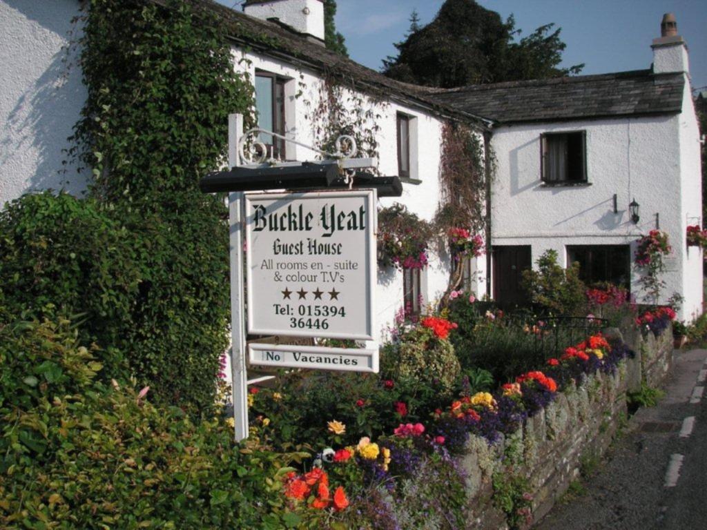 a sign in front of a white house with flowers at Buckle Yeat in Sawrey