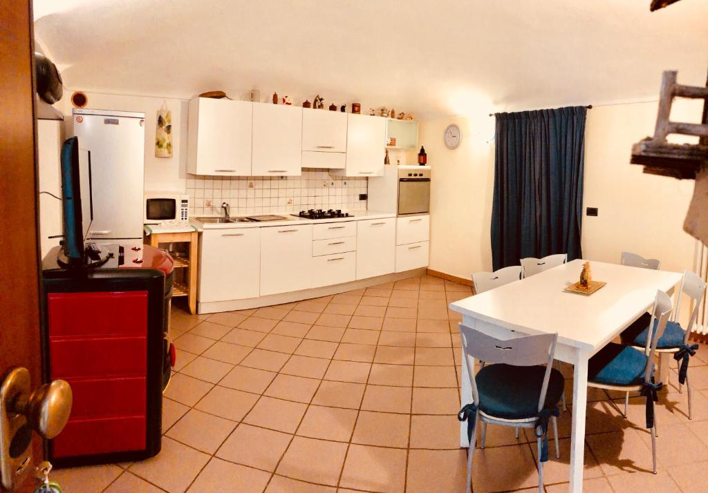 una cucina con armadi bianchi e tavolo con sedie di Appartamento in centro Nus a Nus