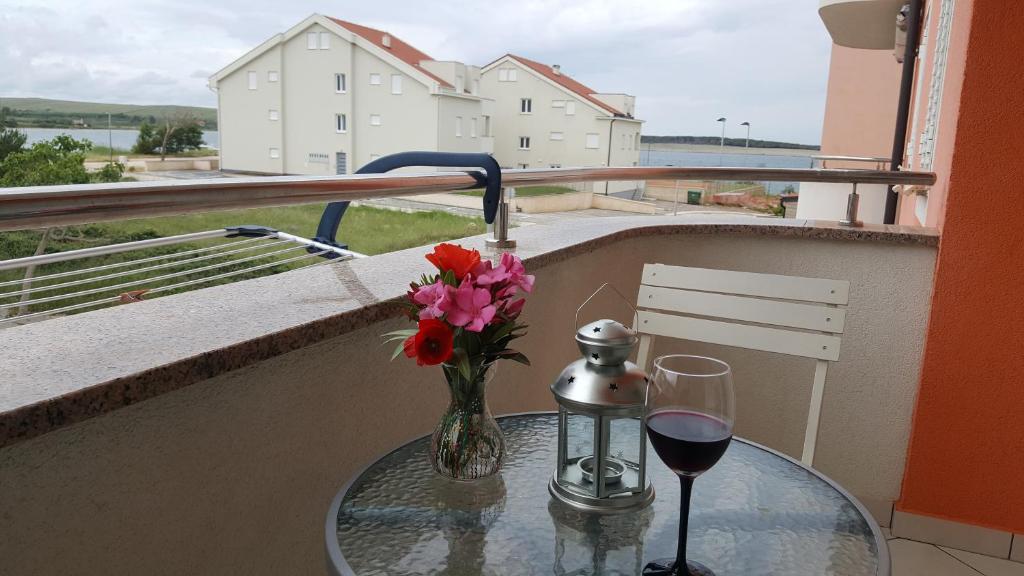 una mesa de cristal con un jarrón de flores y una copa de vino en Roky, en Povljana