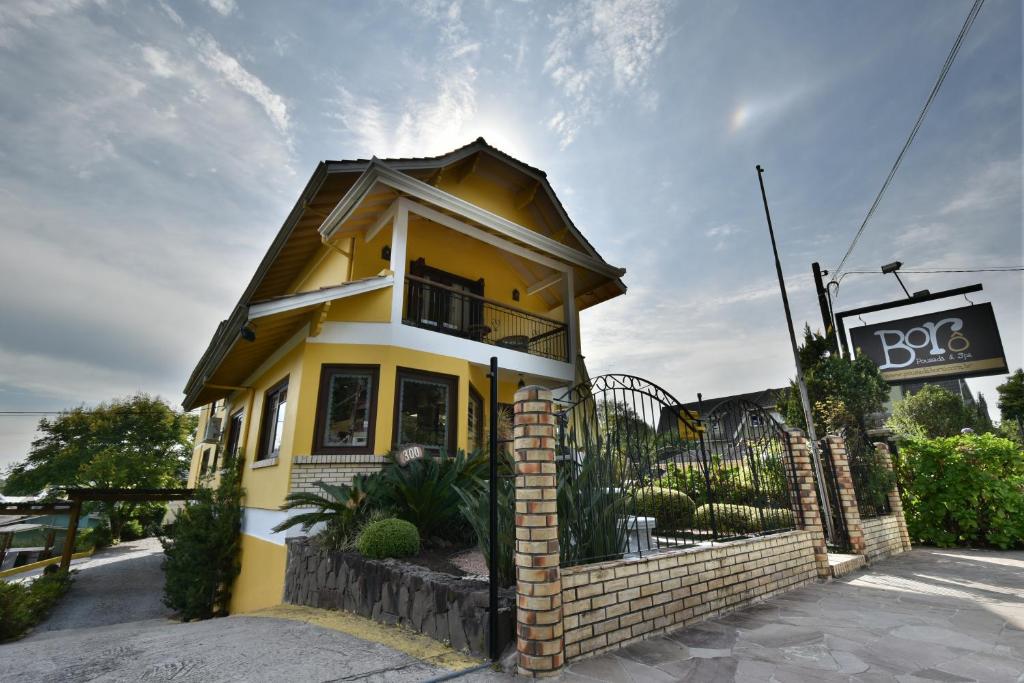 uma casa amarela com um sinal em frente em Pousada Borô em Gramado