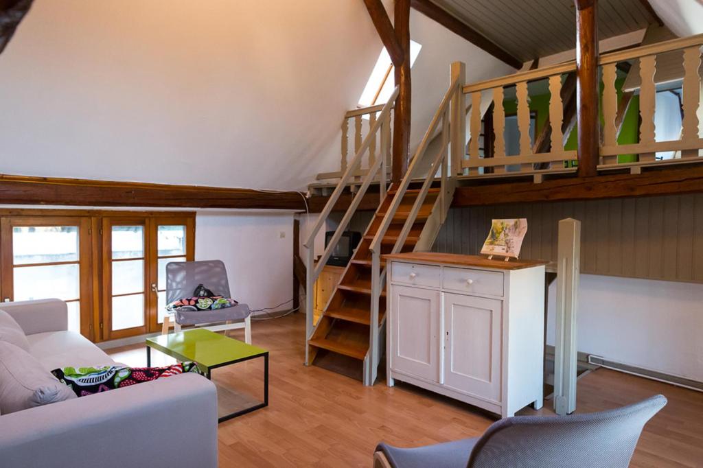 ein Wohnzimmer mit einem Sofa und einer Treppe in der Unterkunft Gîte - Logement rénové dans ferme alsacienne in Pfettisheim