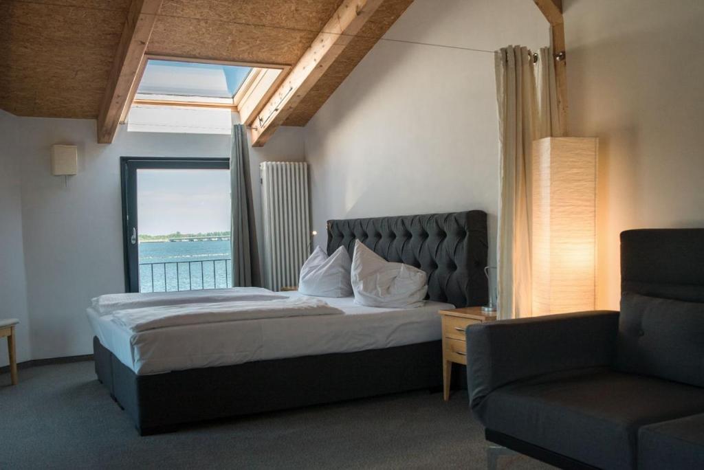 a bedroom with a bed and a chair and a window at Hotel Alter Hafenspeicher in Stralsund