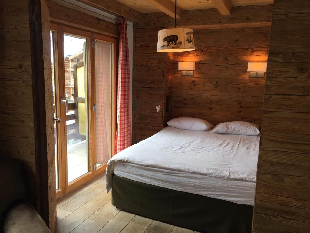een bed in een houten kamer met een raam bij Verbier Valmont in center in Verbier
