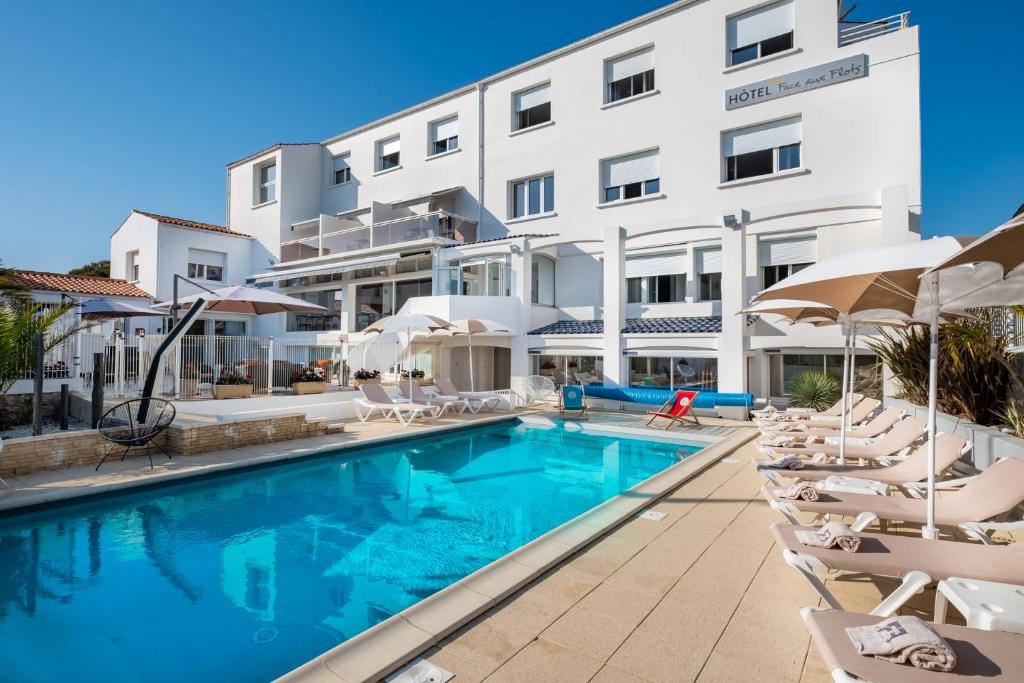 a swimming pool in front of a hotel at Face aux Flots in La Cotinière