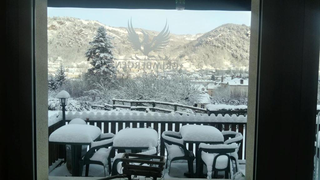 uma mesa e cadeiras cobertas de neve numa varanda em Hôtel St Joseph em Vic-sur-Cère