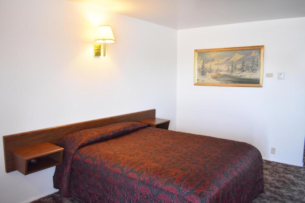 een hotelkamer met een bed en een foto aan de muur bij JR Inn in Soda Springs