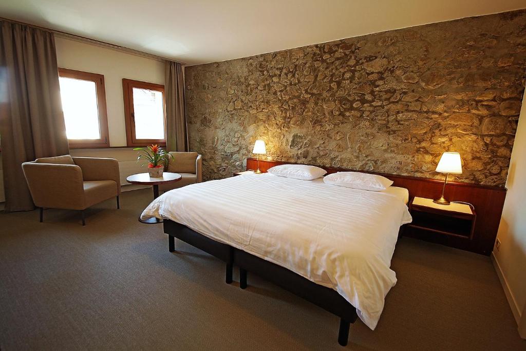 a hotel room with a bed and a stone wall at Galion Hôtel & Restaurant in Lausanne