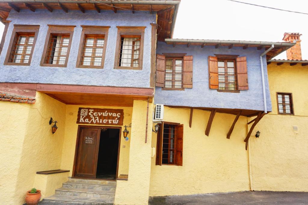 un bâtiment jaune avec un panneau devant lui dans l'établissement Kallisto Traditional Guesthouse, à Litochoro