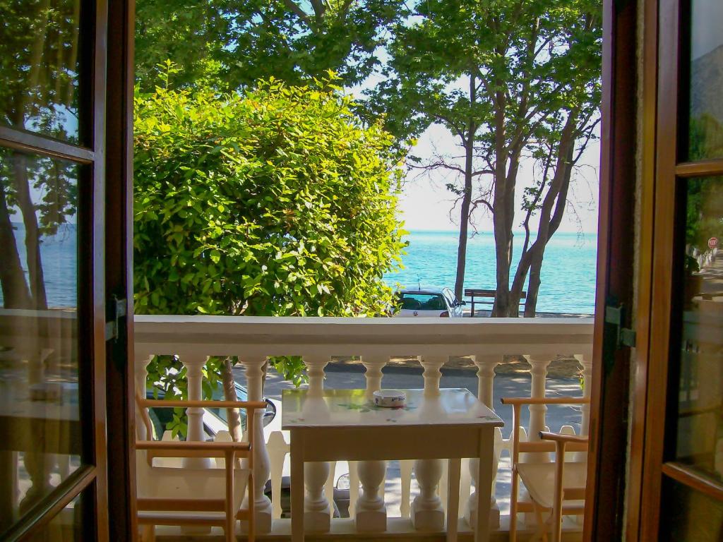 una mesa y sillas en un balcón con vistas al océano en Antigoni House, en Póros