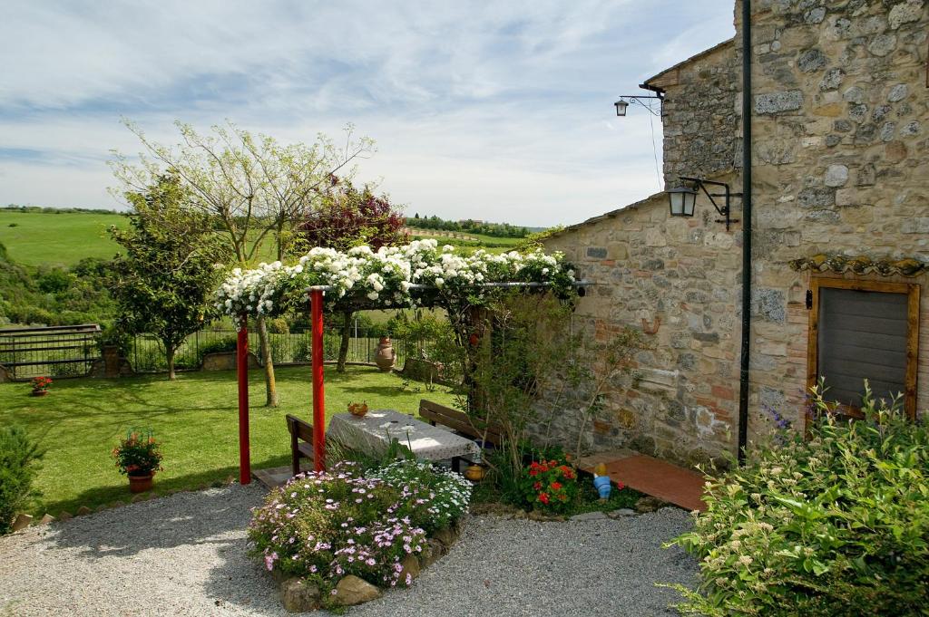 einen Garten mit einem Bogen mit Blumen vor einem Gebäude in der Unterkunft Camere Alabastro Fontesettimena in Volterra