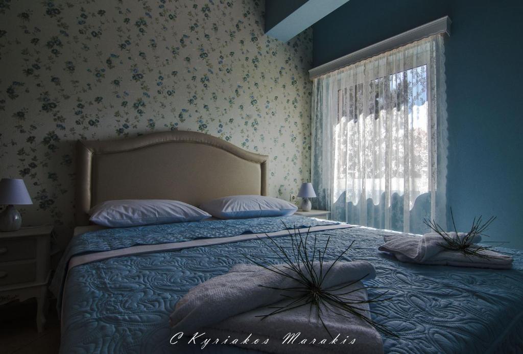 a bedroom with a bed with a blue bedspread and a window at La Casa Del Vitsi in Palaiochóra